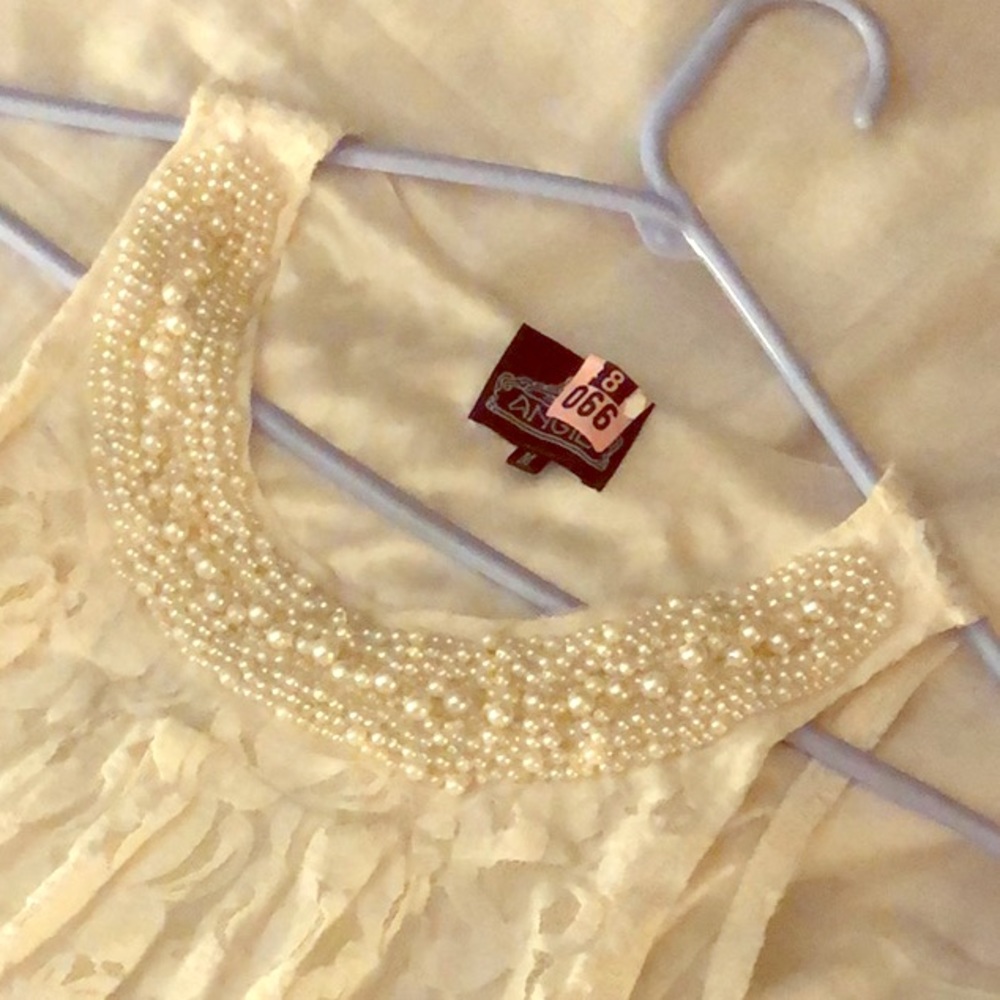 A flowey cream dress with pearls on the front.